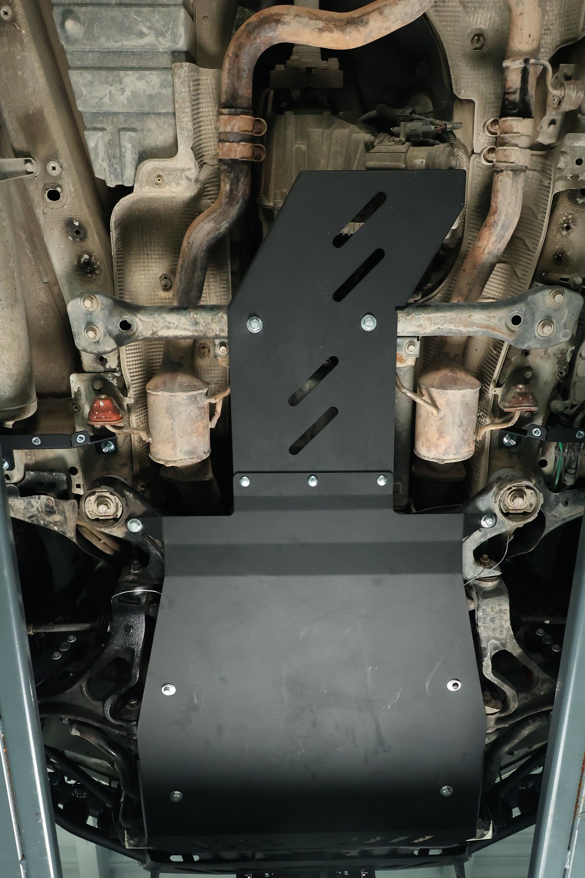 Close-up of a vehicle's undercarriage with protective skid plates.